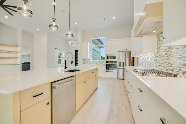 kitchen featuring appliances with stainless steel finishes, a kitchen island with sink, pendant lighting, sink, and tasteful backsplash