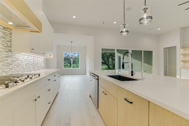 kitchen with custom range hood, light hardwood / wood-style flooring, backsplash, sink, and pendant lighting