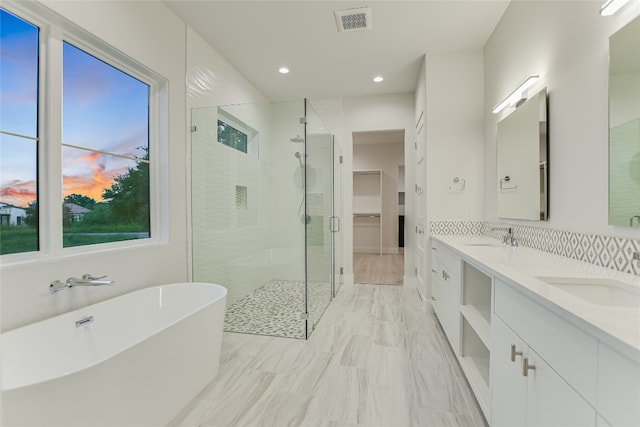 bathroom with tile flooring, tasteful backsplash, double vanity, and independent shower and bath