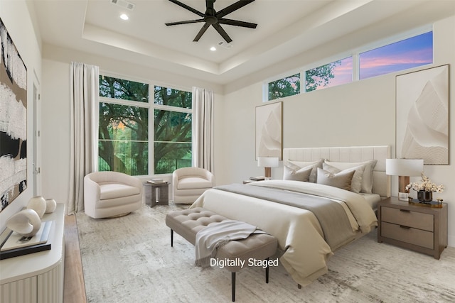 bedroom with ceiling fan, a tray ceiling, and wood-type flooring