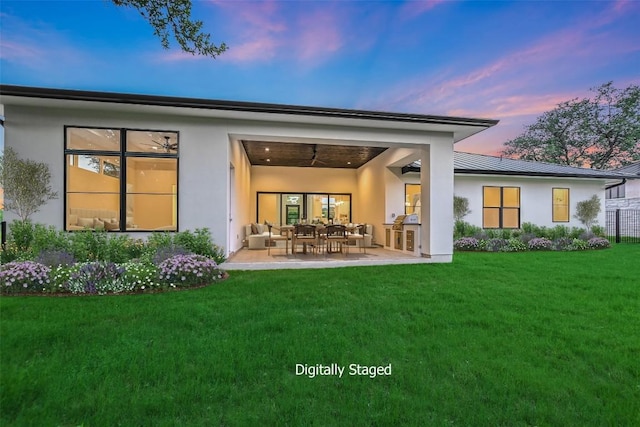 back house at dusk with an outdoor hangout area, a lawn, and a patio