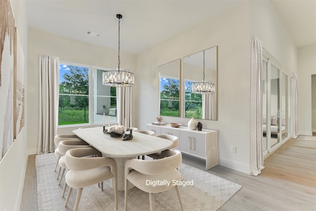 dining room featuring a notable chandelier, a healthy amount of sunlight, and light hardwood / wood-style flooring