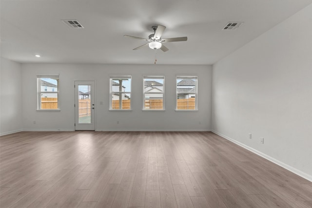 empty room with light hardwood / wood-style flooring, a healthy amount of sunlight, and ceiling fan