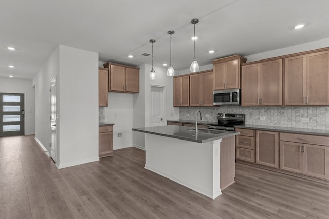 kitchen with hanging light fixtures, an island with sink, hardwood / wood-style flooring, sink, and stainless steel appliances