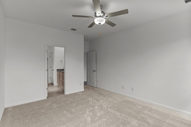 unfurnished bedroom with connected bathroom, ceiling fan, and light colored carpet