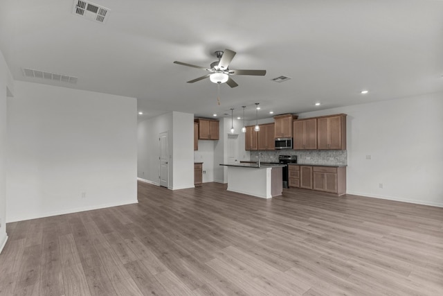 unfurnished living room featuring sink, light hardwood / wood-style floors, and ceiling fan