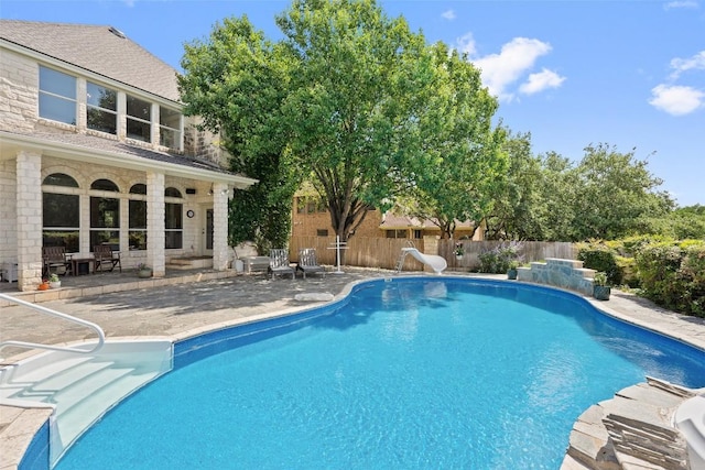 view of swimming pool featuring a patio, a water slide, fence, and a fenced in pool