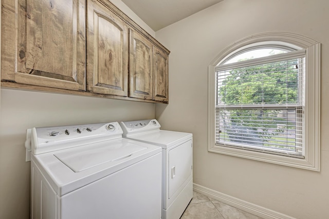 clothes washing area with cabinets, light tile patterned flooring, a wealth of natural light, and washing machine and clothes dryer