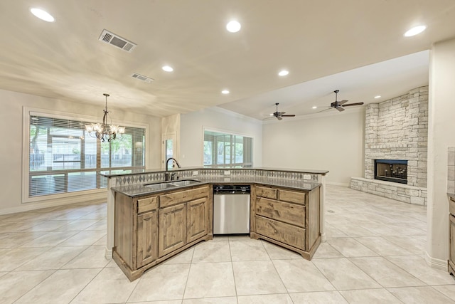 kitchen featuring dishwasher, decorative light fixtures, a stone fireplace, sink, and light tile patterned flooring