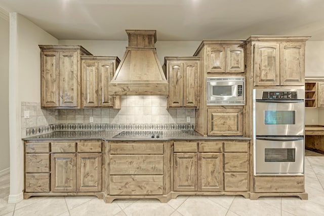 kitchen featuring custom exhaust hood, light tile patterned floors, decorative backsplash, and appliances with stainless steel finishes