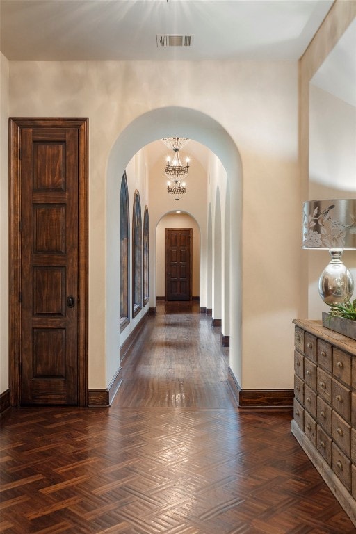 hallway featuring a chandelier and dark parquet floors