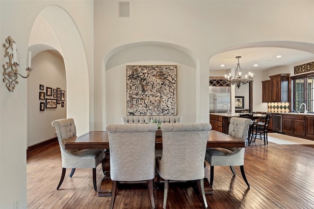 dining space with sink, hardwood / wood-style floors, and an inviting chandelier