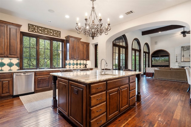 kitchen featuring sink, dishwasher, ceiling fan with notable chandelier, dark hardwood / wood-style floors, and a center island with sink