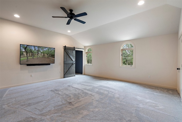 interior space with carpet, a barn door, ceiling fan, and lofted ceiling