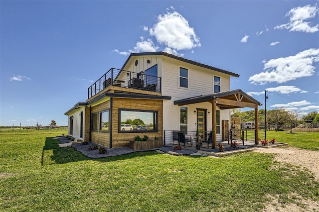 rear view of house featuring a lawn and a balcony