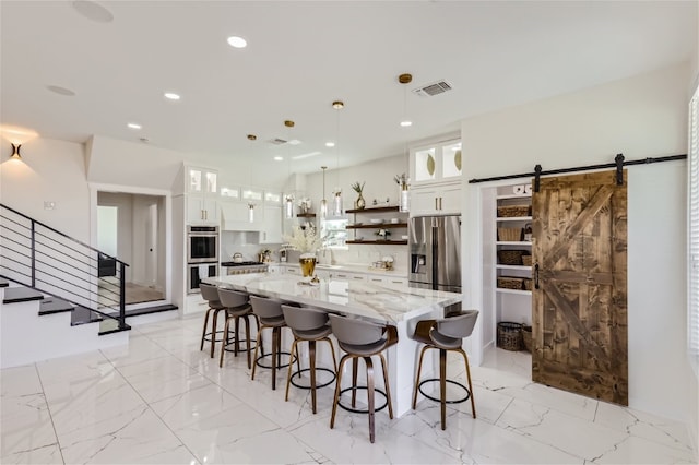 kitchen featuring light stone countertops, white cabinetry, a barn door, pendant lighting, and appliances with stainless steel finishes