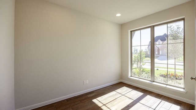 spare room featuring a wealth of natural light and dark hardwood / wood-style floors