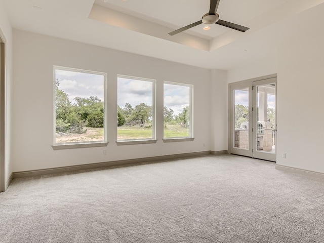 empty room featuring light carpet, ceiling fan, and a raised ceiling