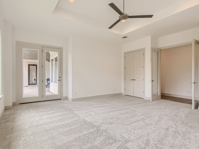 unfurnished bedroom with french doors, light colored carpet, ceiling fan, and a raised ceiling