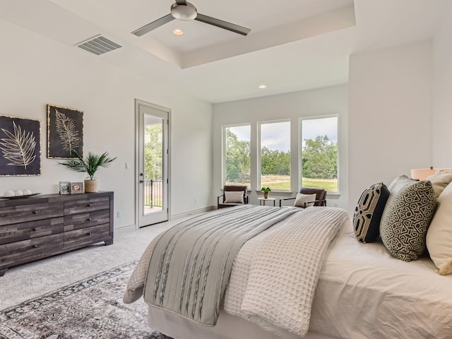 bedroom featuring ceiling fan, carpet flooring, access to outside, and a tray ceiling