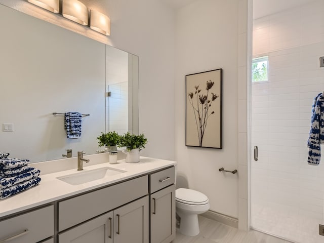 bathroom with an enclosed shower, vanity, and toilet