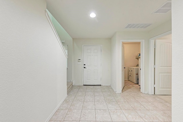 hallway with washer / dryer and light tile patterned floors