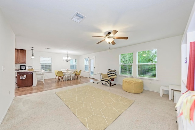 sitting room with ceiling fan with notable chandelier and light colored carpet