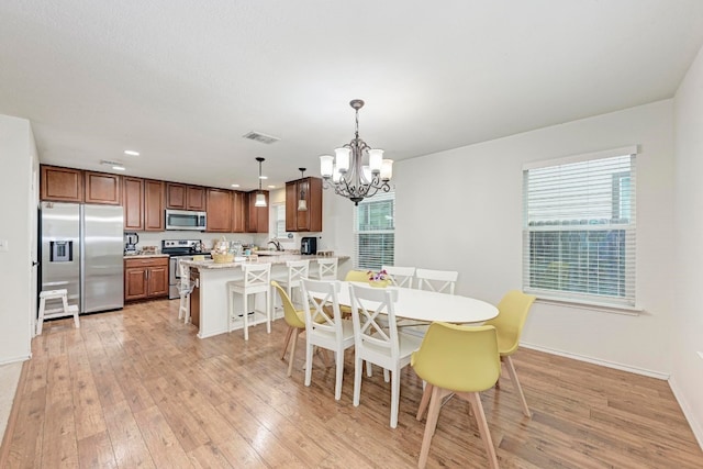 dining space with an inviting chandelier, light hardwood / wood-style flooring, and a healthy amount of sunlight