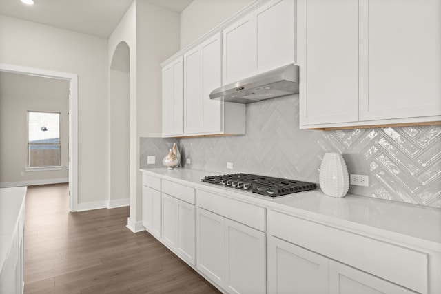 kitchen featuring dark hardwood / wood-style floors, backsplash, white cabinets, and stainless steel gas stovetop