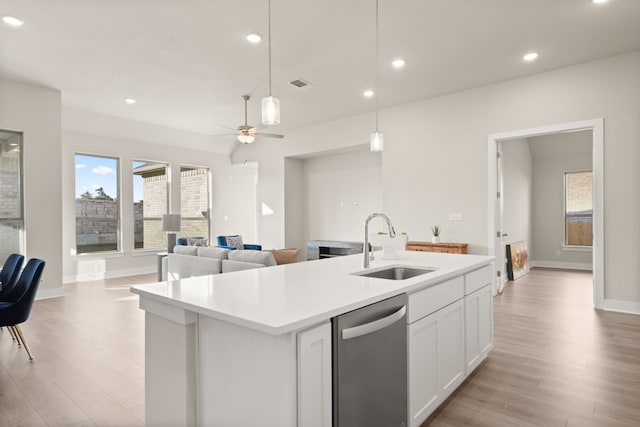 kitchen featuring white cabinets, sink, hanging light fixtures, stainless steel dishwasher, and a center island with sink