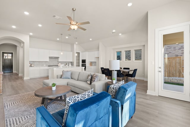 living room with ceiling fan, vaulted ceiling, and light hardwood / wood-style floors