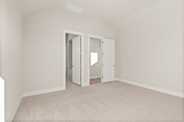 unfurnished bedroom featuring light carpet and vaulted ceiling