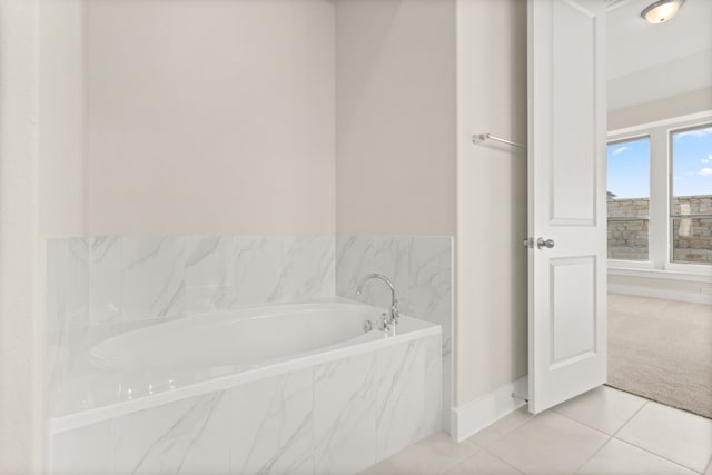 bathroom with tile patterned floors and a relaxing tiled tub