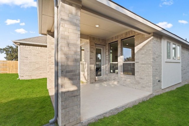 entrance to property featuring a yard and a patio