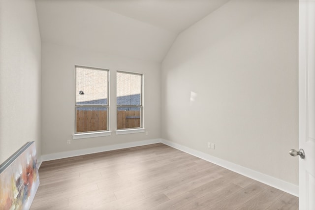 spare room featuring light hardwood / wood-style floors and lofted ceiling