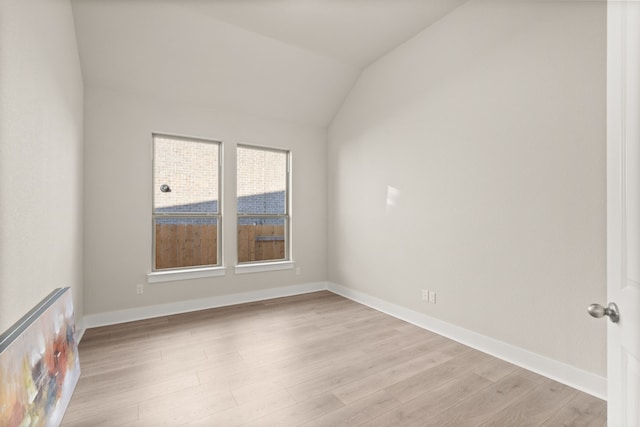 unfurnished room with light wood-type flooring and vaulted ceiling