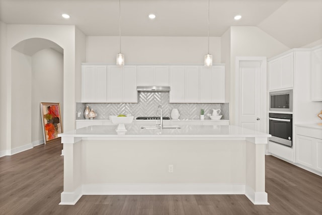 kitchen featuring decorative light fixtures, a kitchen island with sink, and oven