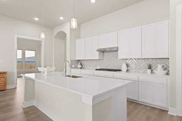 kitchen with white cabinetry, sink, hanging light fixtures, and a center island with sink