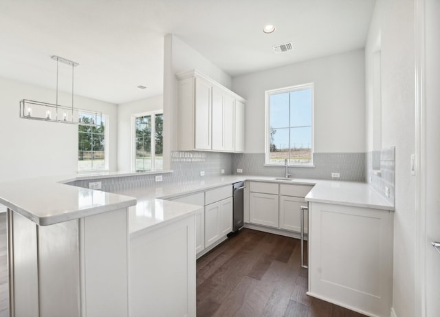 kitchen with white cabinets, decorative backsplash, kitchen peninsula, and dark wood-type flooring