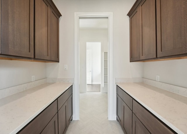 kitchen featuring dark brown cabinets and light stone countertops