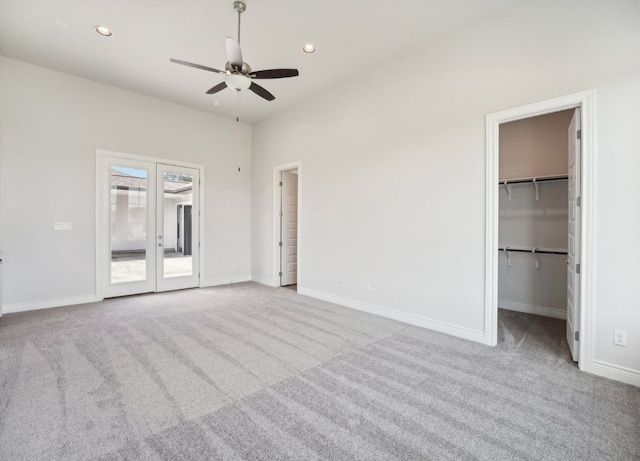 unfurnished bedroom featuring ceiling fan, light colored carpet, a spacious closet, and a closet