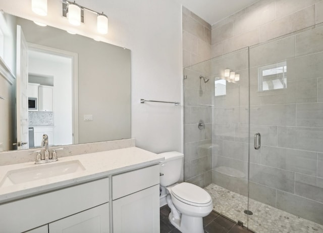 bathroom featuring tile patterned flooring, a shower with door, vanity, and toilet