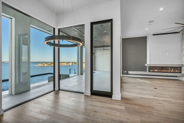 entryway with light wood-type flooring, a water view, and ceiling fan with notable chandelier