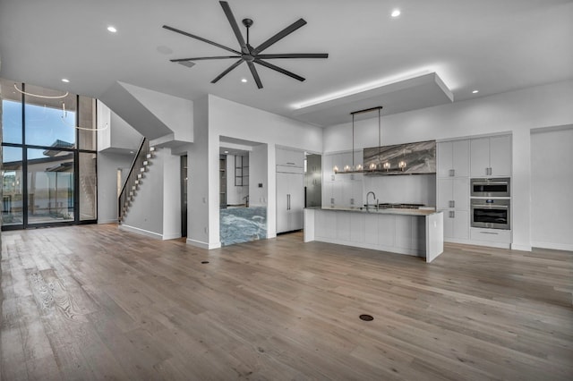 unfurnished living room featuring hardwood / wood-style flooring, ceiling fan, and sink