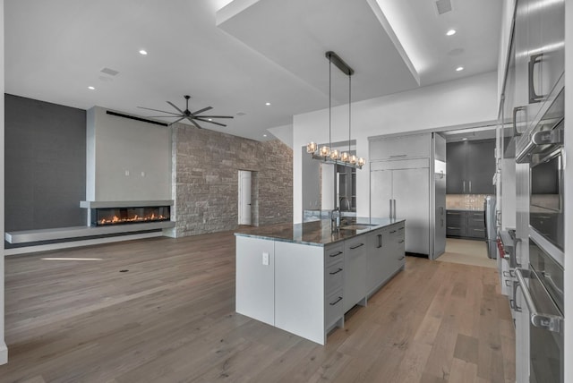 kitchen featuring light hardwood / wood-style floors, sink, dark stone countertops, a large fireplace, and pendant lighting