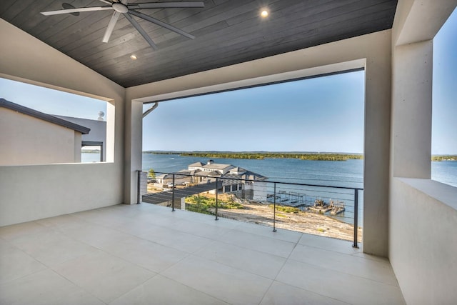 view of patio with ceiling fan, a balcony, and a water view