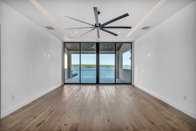 unfurnished room featuring plenty of natural light, a water view, hardwood / wood-style flooring, and ceiling fan