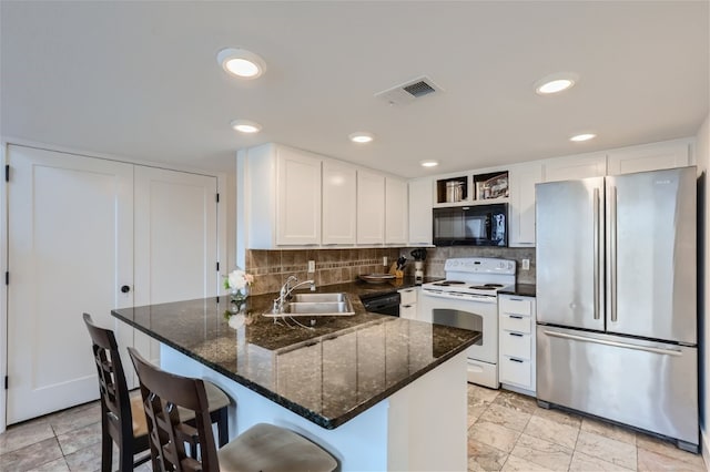 kitchen with sink, white cabinetry, a breakfast bar area, and black appliances