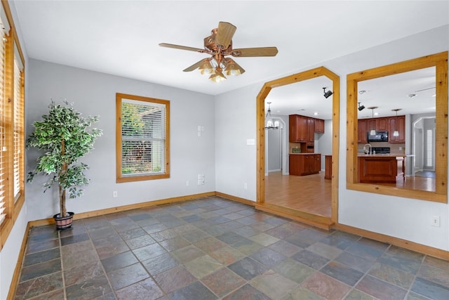 empty room with sink, dark tile floors, and ceiling fan with notable chandelier