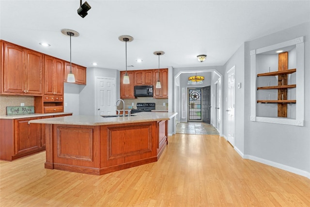 kitchen featuring decorative light fixtures, black appliances, and light hardwood / wood-style flooring